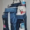 A navy nursery organizer hanging on a door. The organizer is filled with nappies, a teddy bear and bum cream.