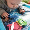 A toddler lying on his tummy looking at the foam toys inside the inflatable water play mat.
