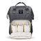 A grey backpack nappy bag. The front pocket is open. There are 3 baby bottles inside.
