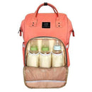 A peach backpack nappy bag. The front pocket is open. It has 3 baby bottles inside.
