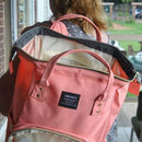 A lady carrying a peach backpack nappy bag over her shoulder. The bag is open.