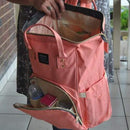 A lady carrying a peach backpack nappy bag. The bag is open.