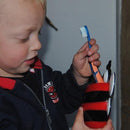 A young boy placing his toothbrush in a red bee toothbrush holder.